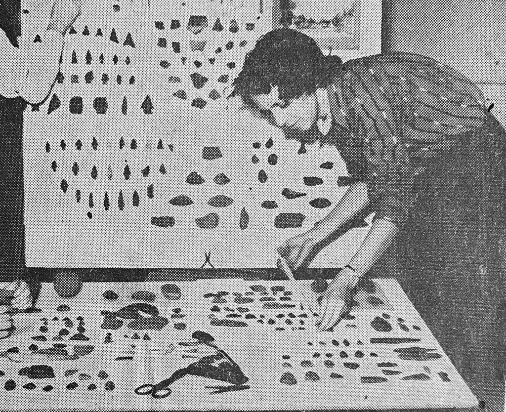 Mary Butler Lewis examining a table of artifacts.