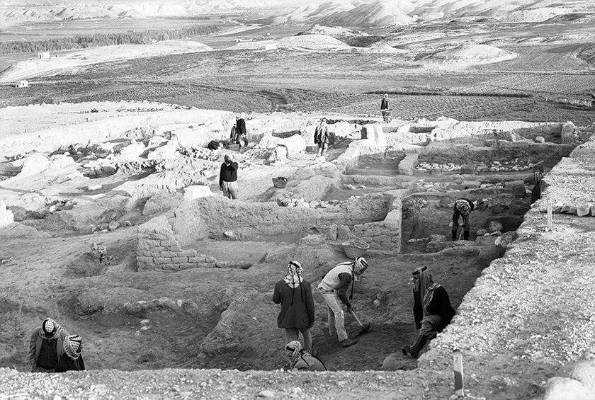 Workers excavating around remains of houses.