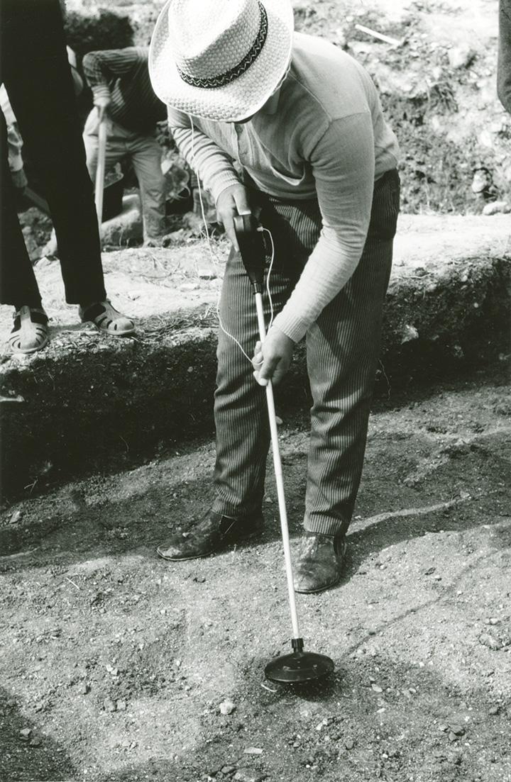 An excavation worker using a metal detector.