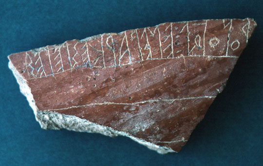 A pottery fragment with three rows, the top row containing a series of inscriptions.