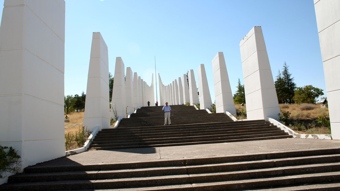 The broad stairs leading up the mound, with tall white columns lining the sides, a man stands in the middle of the staircase.
