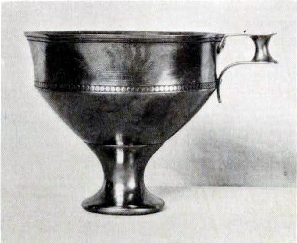 A stemmed silver cup with plant decoration and one handle