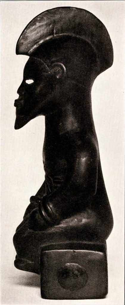Carved wood seated figure with a crested hair or headpiece, in profile