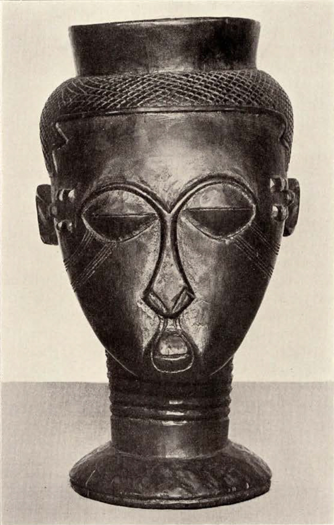 A cup in the shape of a head and face with long neck, from the front