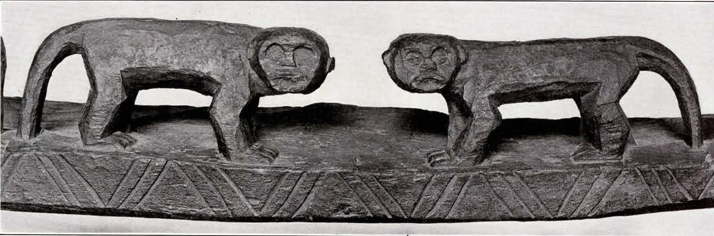 Wood carved door lintel, middle, two monkeys with bodies facing each other but heads turned outward