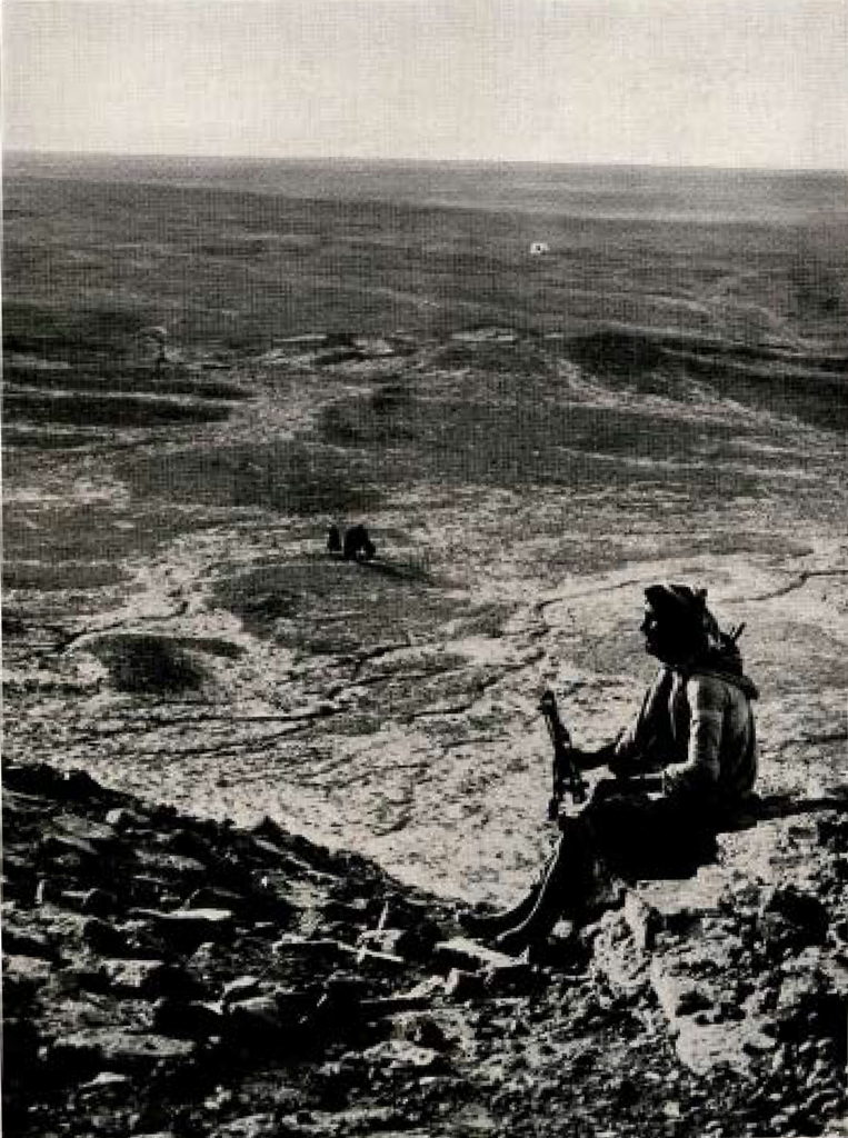 A man sitting on a hill, overlooking the desert