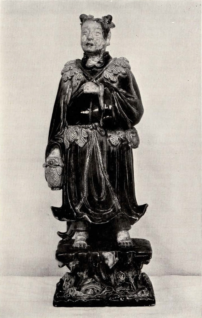 standing female figure with hair in two buns on top of her head, wearing loose robes tied at the waist and decorated with leaves