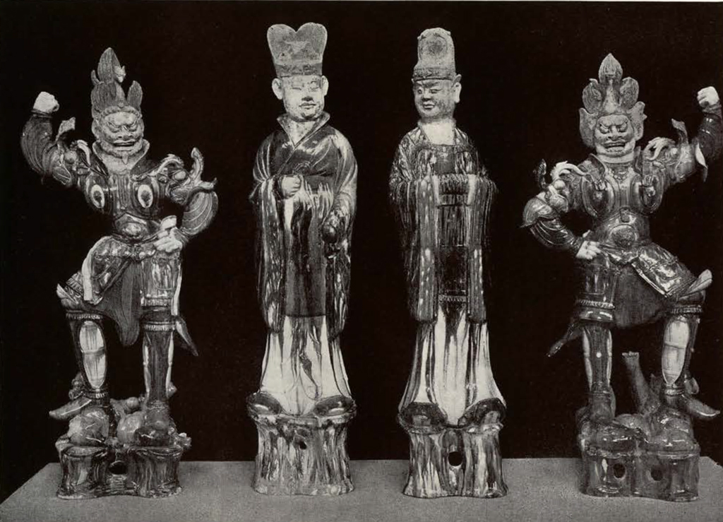 Four clay figures in a row, two lokapalas on either end and two robed officials in the middle