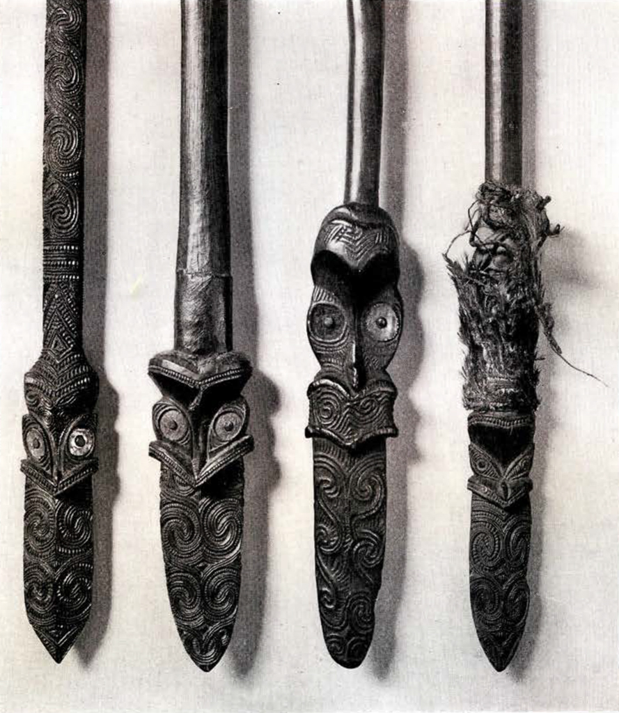 Four heads or blades, close up, showing the pattern and face carvings in each