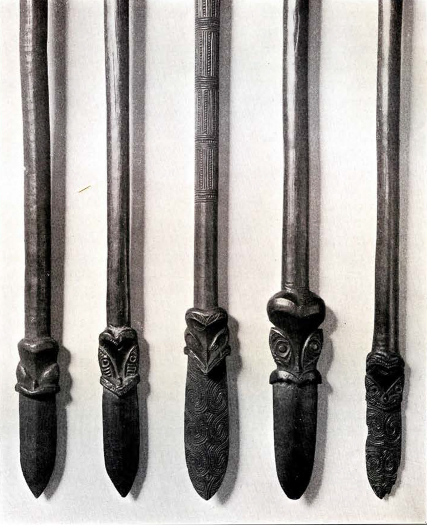 Five heads or blades, close up, showing the pattern and face carvings in each