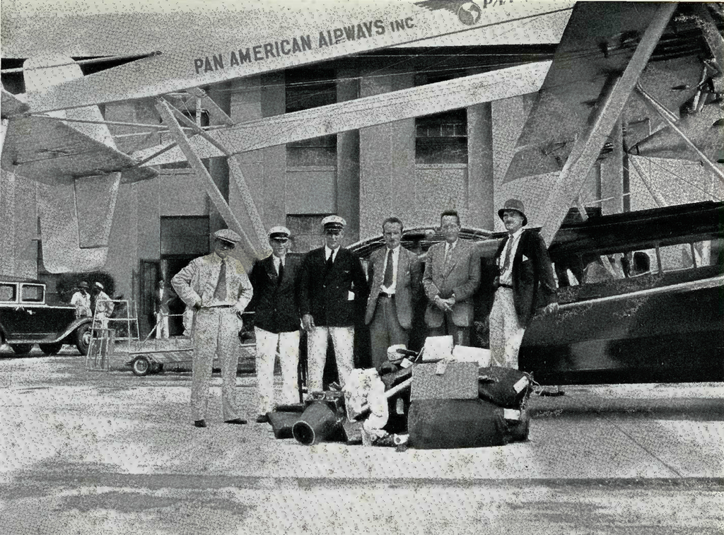 A group of men standing with a pile of luggage in front of a plane