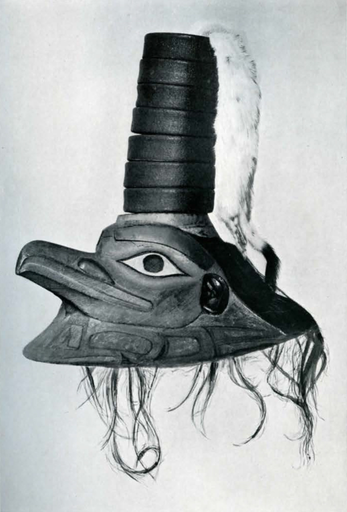 Hat in the shape of a raven head with beak, stacked rings on top with an animal pelt from the top