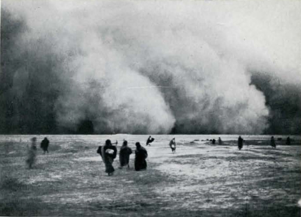 People standing in the desert watching a large sandstorm approach