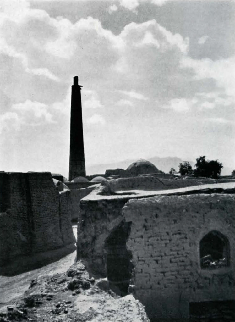 A minaret looming against a sky above building ruins