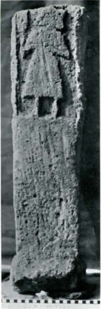 A pice of limestone with a figure carved into the top third