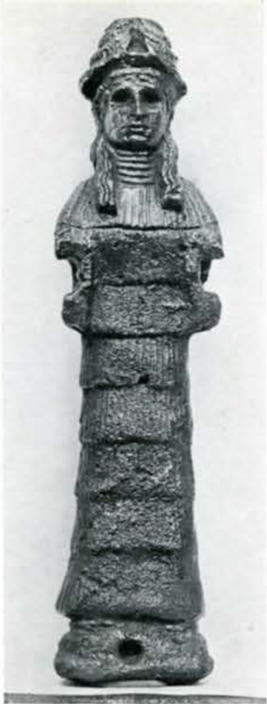 Statuette of a human figure with long hair wearing a headpiece and long pleated layered garb