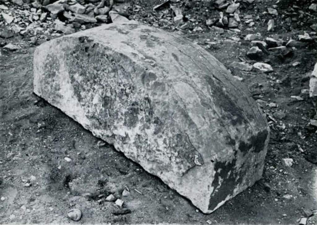 Large rectangular stone with a rounded top, resting on the ground
