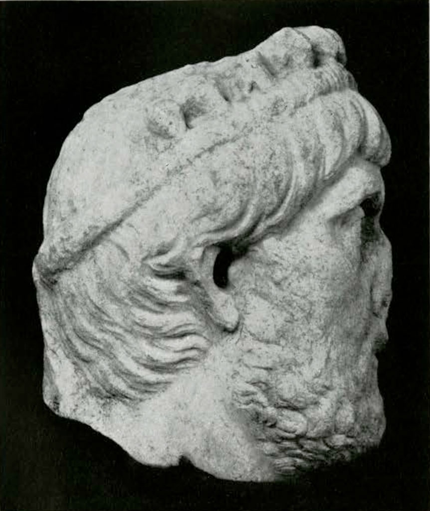 Left profile of stone head with flat nose and crown