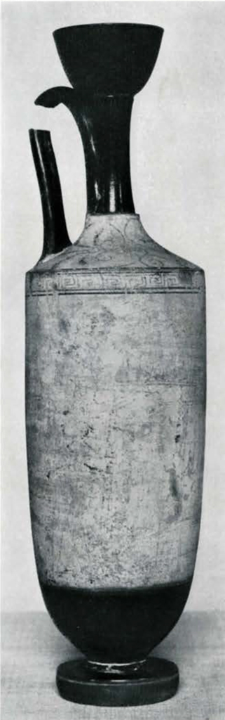A vase with a handle, a piece missing, and a long neck, degraded image but geometric pattern around the top