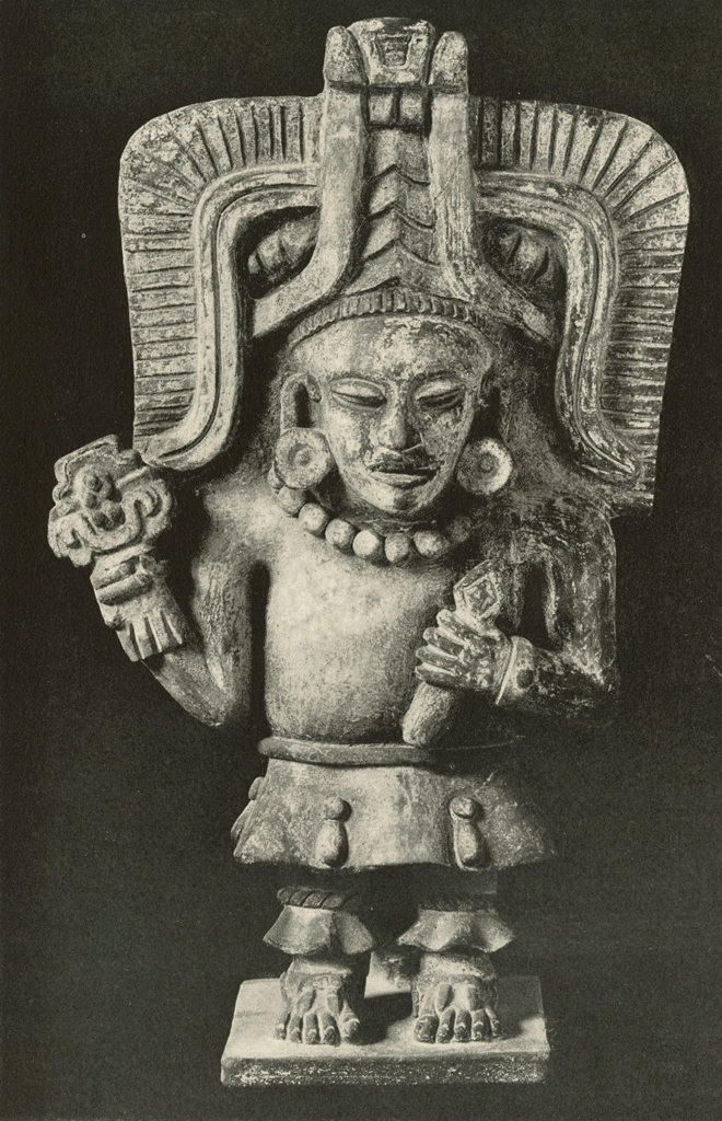 Effigy urn in the shape of a standing man with a large rectangular headdress and holding an object in one hand