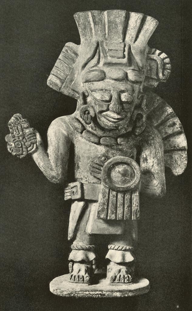 Effigy urn in the shape of a standing man with a tall headdress and holding an object in one hand