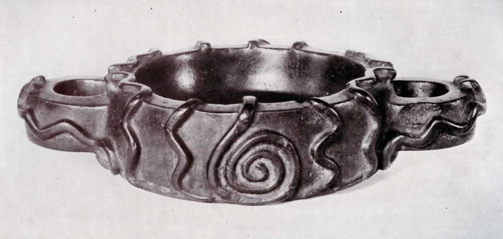 A low flat bowl with two handles, decorated with snakes in relief