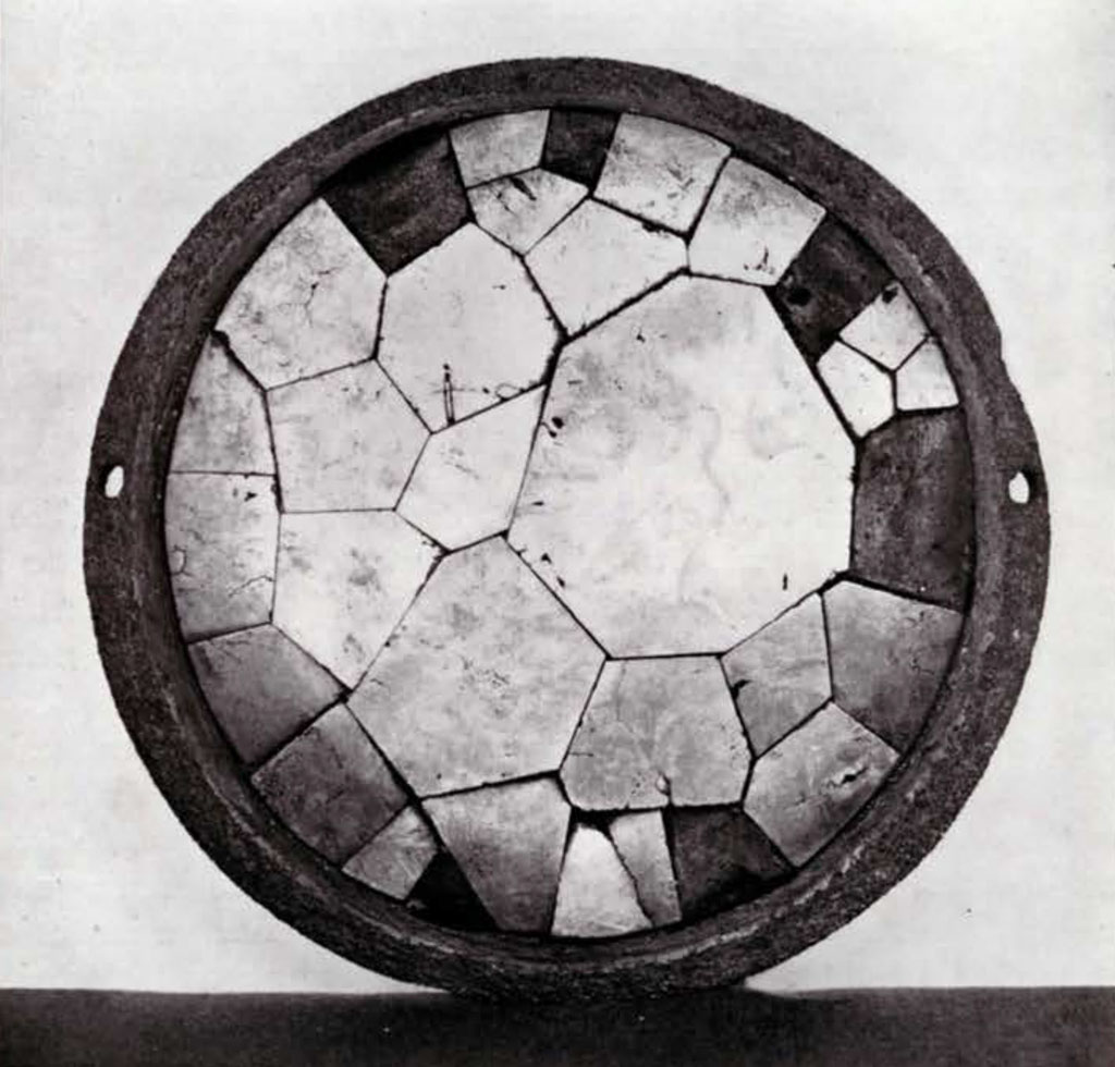 A circular mirror made of several pieces of pyrite pieced together
