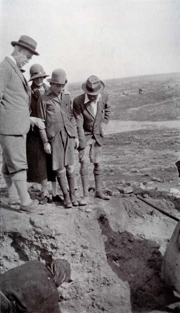 A group of people looking into a tomb in the ground