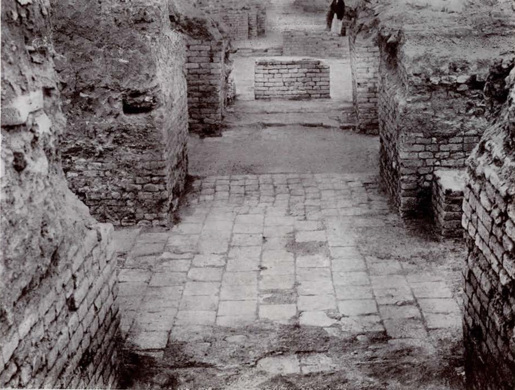 Looking toward a paved court with a brick altar in the middle and brick walls on either side