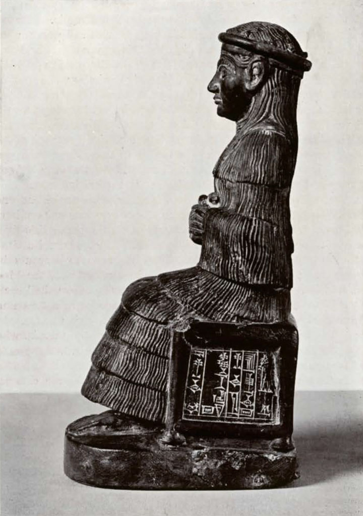 Seated goddess in tiered dress, profile view showing inscription