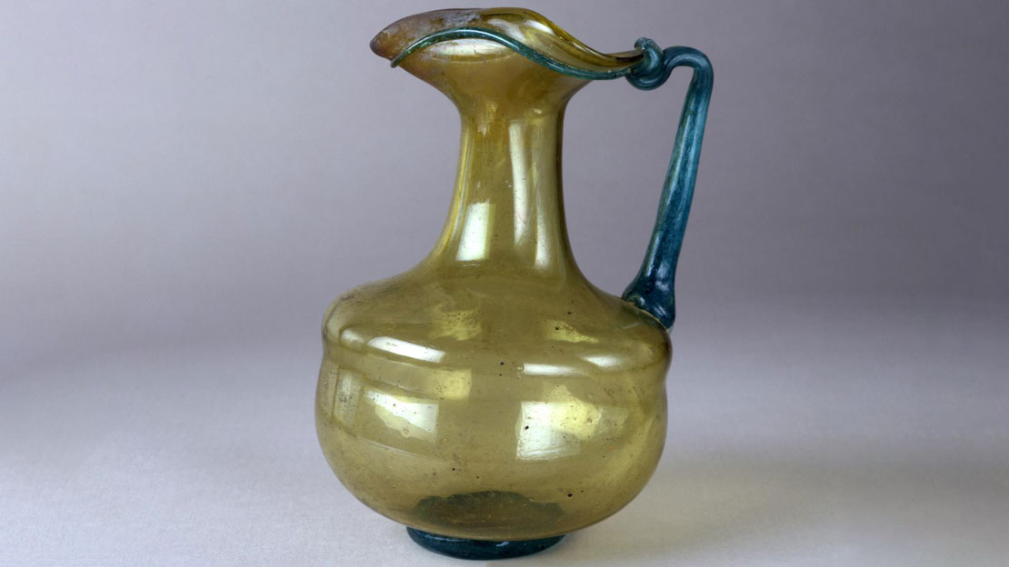 Amber and blue glass squat jug with trefoil mouth. Handles, base and band on rim blue.